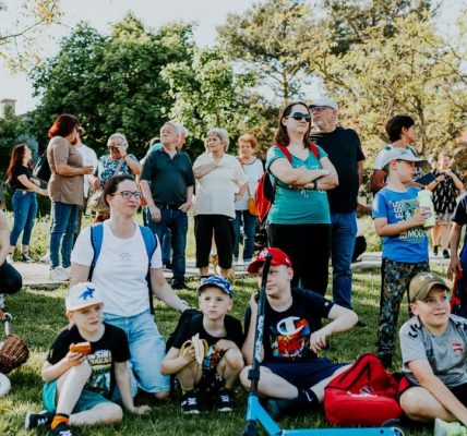 A diverse group of people enjoying a sunny day at an outdoor community event in a park setting.
