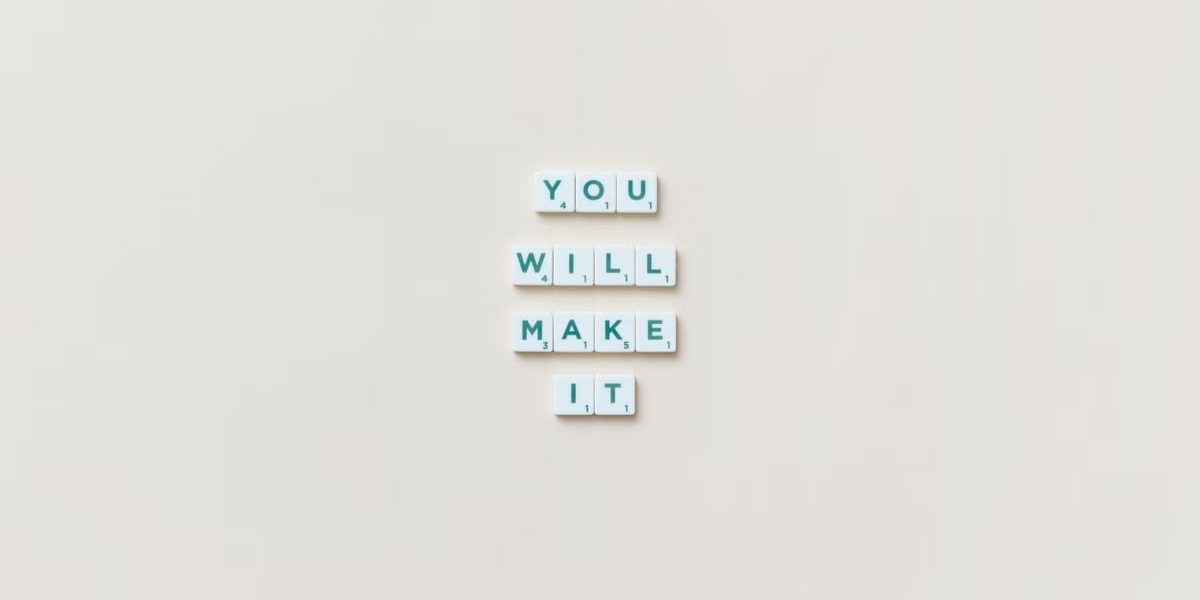 Motivational phrase 'You Will Make It' made from Scrabble tiles on a neutral background.