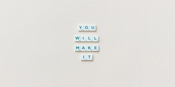 Motivational phrase 'You Will Make It' made from Scrabble tiles on a neutral background.
